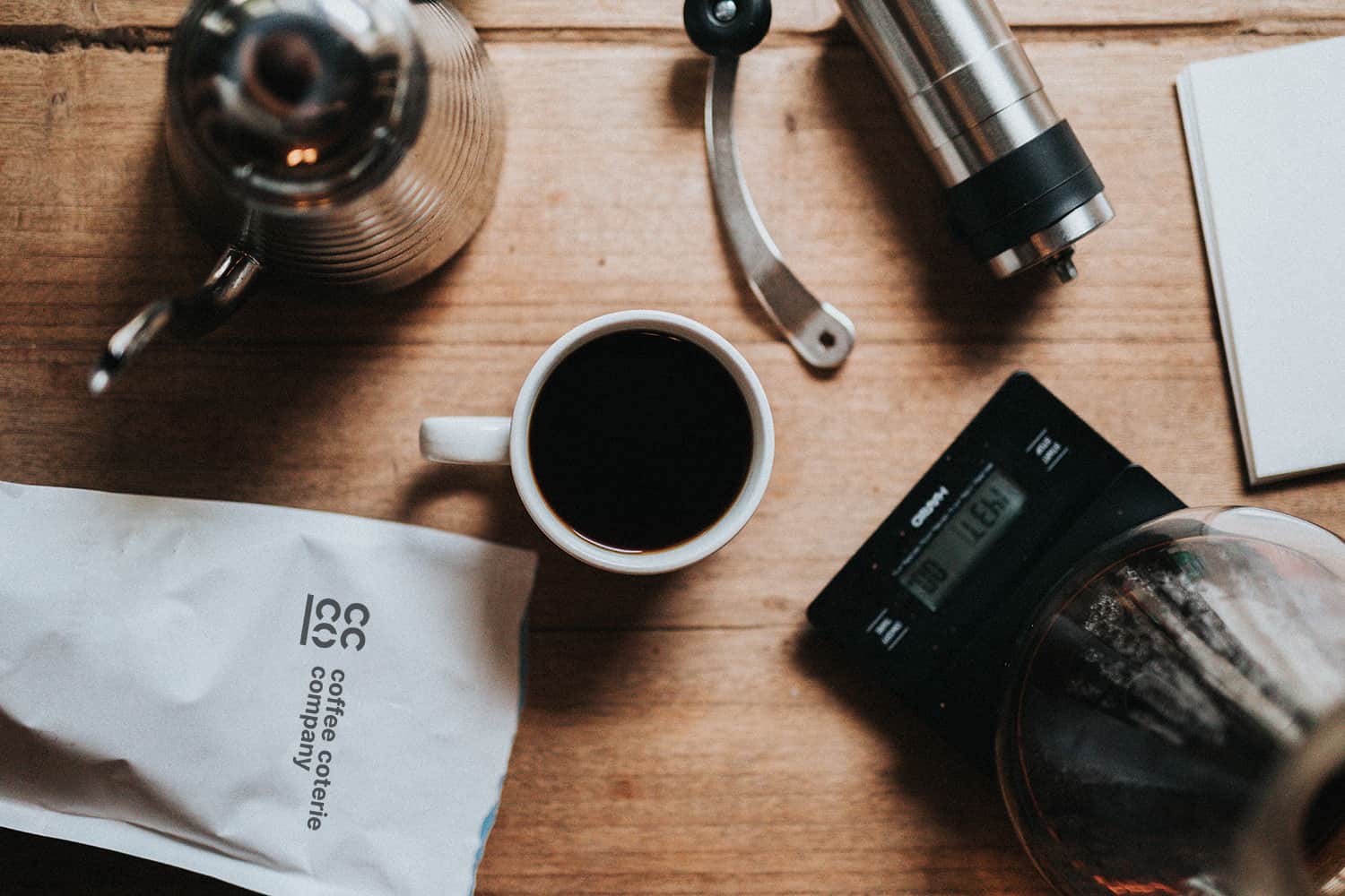 Electric coffee percolator, coffee cup, and grinder on table